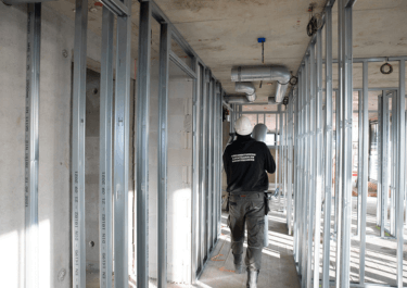 Monteur in een gebouw in aanbouw die luchtkanalen aan het monteren is