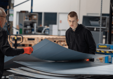 Leerling die metalenplaat aan het tillen is op de werkplaats van Schilt