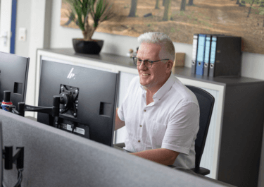 Medewerker op kantoor Schils aan bureau en achter beeldscherm