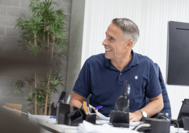 Lachende medewerker aan een bureau op kantoor Schilt