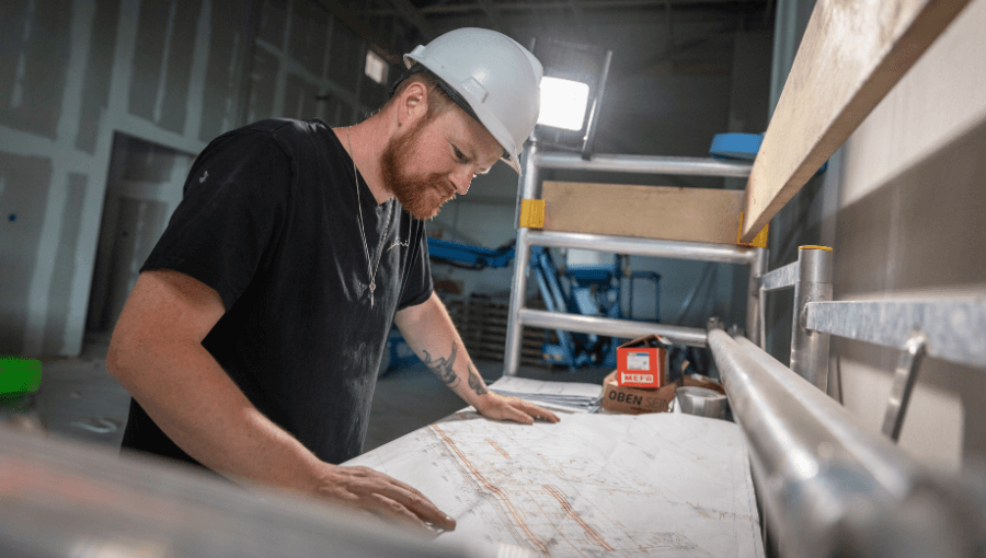 Monteur Schilt luchtkanalen over een tekening heen gebogen