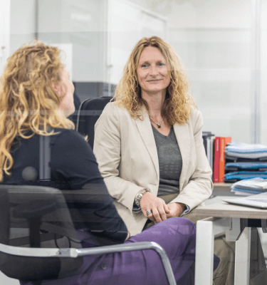 Twee medewerksters op kantoor die aan het overleggen zijn