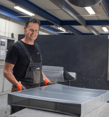 Medewerker werkplaats die een plaat metaal in zijn handen heeft