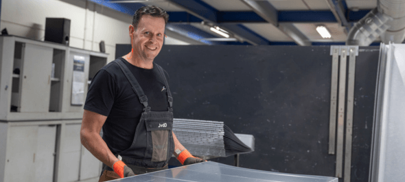 Medewerker werkplaats die een plaat metaal in zijn handen heeft