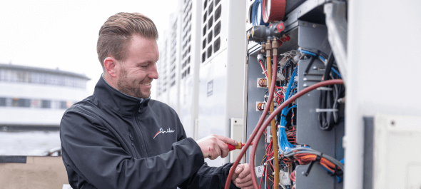 Schilt monteur service en onderhoud die op een dak aan het werk is met een schroevendraaier in zijn hand