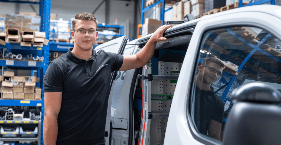 Schilt monteur airconditioning in het magazijn leunend tegen zijn bus